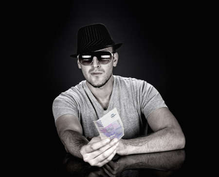 man in hat and sunglasses holding out one thousand czech krona bank noteの写真素材