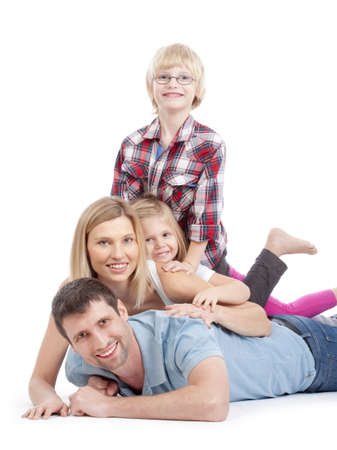 happy family having fun lying on top of each other in a stack - isolated on whiteの写真素材