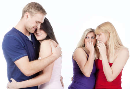 two young woman gossip about a couple embracing - isolated on whiteの写真素材
