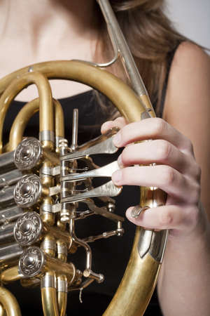 detail of a female musician«s fingers playing concert french horn の写真素材