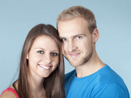 portrait of a happy young couple smiling, looking - isolated on blueの写真素材