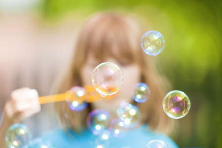boy with long blond hair blowing soap bubbles
