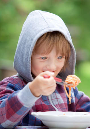 Boy with Blond Hair in Hood Eating Pastaの写真素材