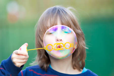 Boy with Blond Hair Blowing Bubbles Outdoorの写真素材