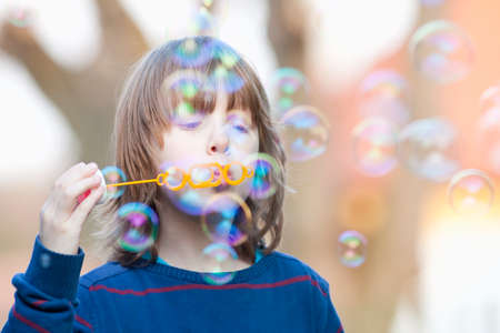 Boy with Blond Hair Blowing Bubbles Outdoorの写真素材