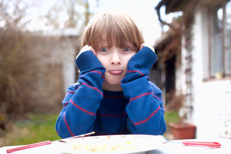 Boy Eating Outdoors Making Facesの写真素材