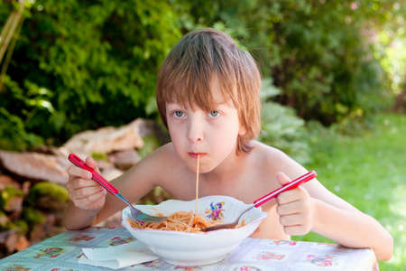 Boy with Blond Hair Eating Pasta Outdoorの写真素材