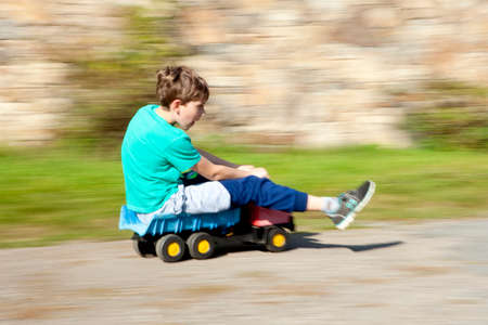 Boy Riding Downhill on Top of Toy Lorryの写真素材