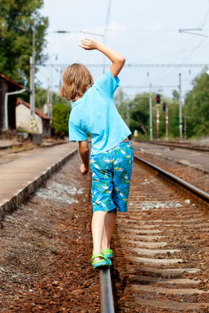 Young Boy Walking on the Railroad Trackの写真素材