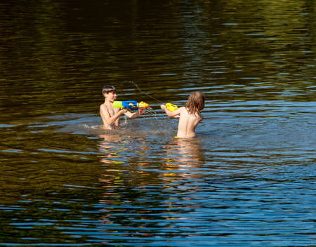 Two Boys Fighting with Squirt Guns in the Lake.の写真素材