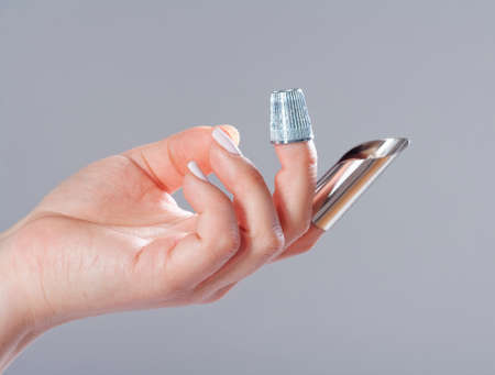 Hand with Two Thimbles on Fingers on Grey Background.