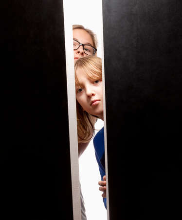 Couple of Curious Children Peeking from Behind Doorsの写真素材