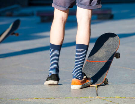 Skateboarding - detail of skateboard and legs with trainers.