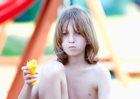 Boy with Long Blond Hair Playing  with Squirt Gun.の写真素材