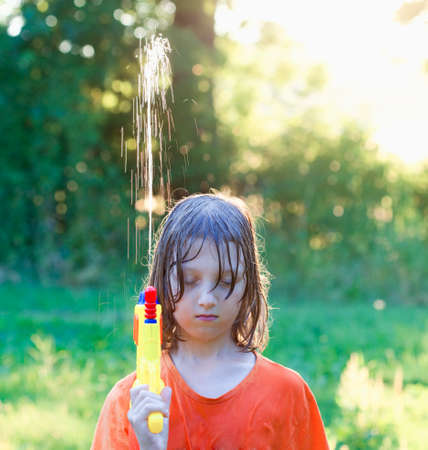 Wet Boy Fooling Around with Water Gun Squirting.の写真素材