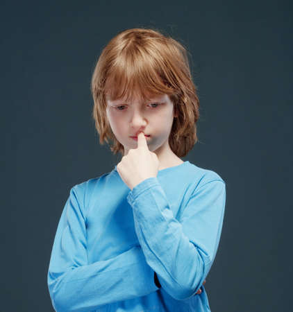 Portrait of a Boy with Long Blond Hair in Blue Top Thinking.