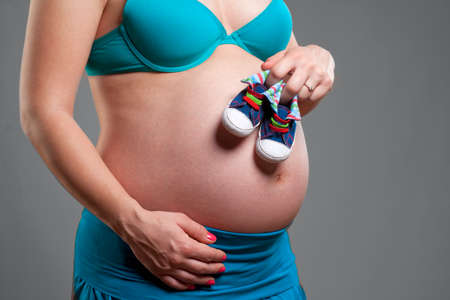Pregnant Woman with Hands Holding Baby Shoe.の写真素材
