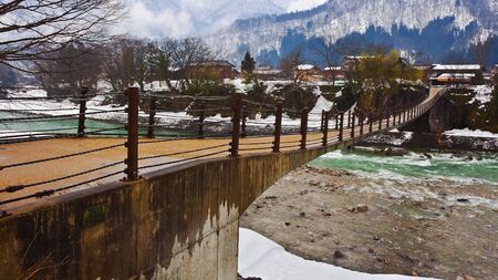 SHIRAKAWA GO, JAPAN - MARCH 28  The bridge over Shokawa river leads people to Gassho-Zukuri Villageのeditorial素材