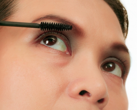 Isolated Asian woman applying mascara on white.の写真素材