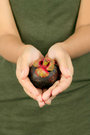 Isolated young asian woman with a mangoesteen over white の写真素材