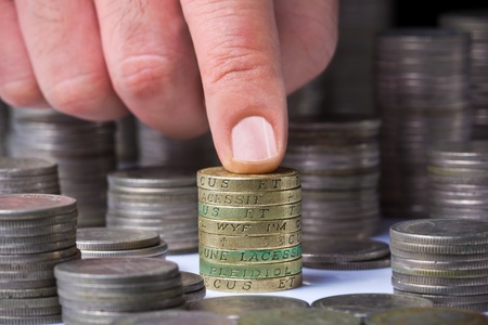 Closeup of stack of british pound coins with a male hand