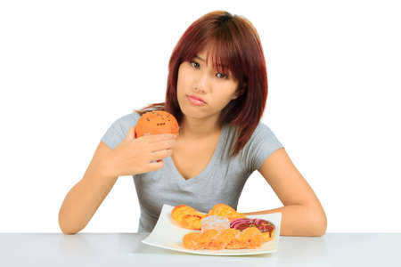 Isolated young asian woman with a donuts on the tableの写真素材