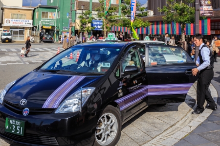 FUKUOKA, JAPAN - NOVEMBER 13: Taxi driver in Fukuoka, Japan on November 13, 2013. Unidentified Japanese taxi driver with passengers in front of Dazaifu stationのeditorial素材