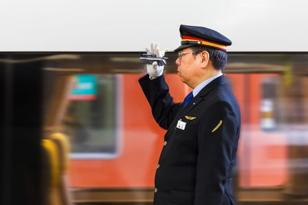 OSAKA, JAPAN - NOVEMBER 16  Train Conductor in Osaka, Japan on November 16, 2013  Unidentified Japanese train conductor gives a hand sign to a train while making a stop at Osaka Stationのeditorial素材
