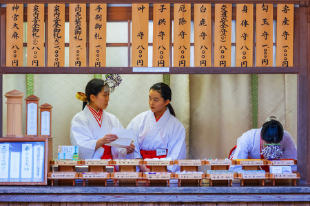NARA, JAPAN - NOVEMBER 16  Shrine maiden in Nara, Japan on November 16, 2013  Unidentified  Miko  at Kasauga Taisha shrine are in a counter selling wide variety of charms that made by the shrineのeditorial素材