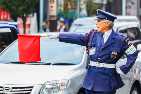 KOBE, JAPAN - NOVEMBER 17  Security Guard in Kobe, Japan on November 17, 2013  Unidentified security guard raises a red flag at a traffic lights for people to cross the street at Motomachi streetのeditorial素材
