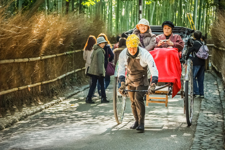 KYOTO, JAPAN - NOVEMBER 19  Rickshaw in Kyoto, Japan on November 18, 2013  Unidentified man with a rickshaw and tourists at Chikurin-no-michi, famous bamboo grove near Tenryuji Templeのeditorial素材