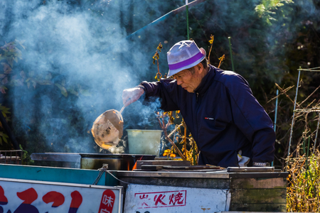 KAWAGUCHIKO, JAPAN - NOVEMBER 22  Senior citizen in Kawaguchiko, Japan on November 22, 2013  Unidentified senior male sets fire boiling corn in the kettle to sell to tourist on the side of the roadのeditorial素材