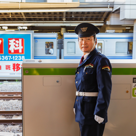 TOKYO, JAPAN - NOVEMBER 23  Train Conductor in Tokyo, Japan on November 23, 2013  Unidentified Japanese train conductor observes passenger before train arrives at the platformのeditorial素材