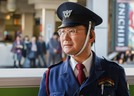TOKYO, JAPAN - NOVEMBER 23  Train Conductor in Tokyo, Japan on November 23, 2013  Unidentified Japanese train conductor observes passenger before train arrives at the platformのeditorial素材