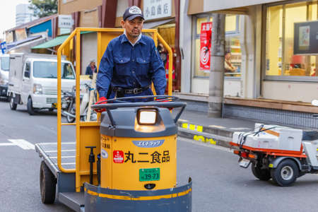 TOKYO, JAPAN - NOVEMBER 25  Tsukiji fish market in Tokyo, Japan on November 25, 2013  Unidentified japanese worker drives a mini truck to transfer food to bigger truckのeditorial素材
