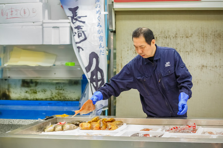 TOKYO, JAPAN - NOVEMBER 25  Tsukiji fish market in Tokyo, Japan on November 25, 2013  Unidentified japanese fish seller categorizes fish before selling to peopleのeditorial素材