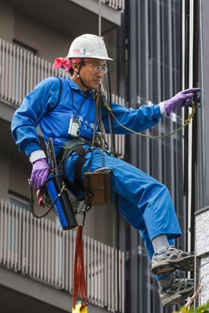 Tokyo, Japan - November 25 2013   Unidentified Japanese window cleaner work on windows of a building