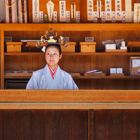 OSAKA, JAPAN - OCTOBER 24: Shrine aiden in Osaka, Japan on October 24, 2014. Unidentified "Miko" at  Sumiyoshi Taisha Shrine in the counter selling wide variety of good luck charms in the shrineのeditorial素材