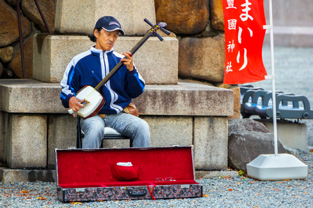 OSAKA JAPAN  OCTOBER 27: Street Musician in Osaka Japan on October 27 2014. Unidentified musician play the Shamisen  traditional Japanese musical instrument in front of Hokokujinja shrineのeditorial素材