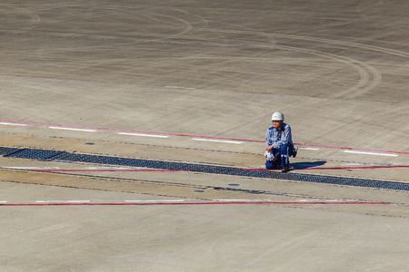 OSAKA, JAPAN - OCTOBER 30: Kansai International Airport in Osaka, Japan on October30, 2014. Unidentified Japanese ground officer stands by before giving signs for a plane to take ofのeditorial素材