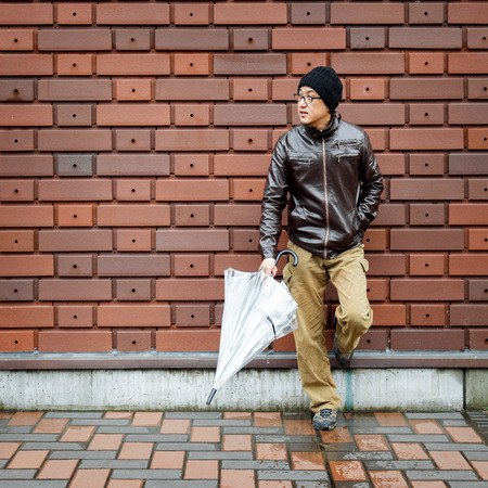 An Asian Man in a Brown Jacket With a Clear Umbrellaの写真素材