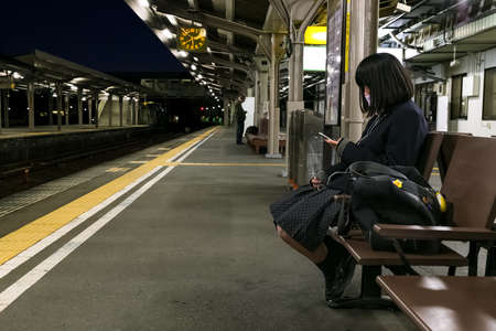 MIE, JAPAN - NOVEMBER 20, 2015: Japanese student on a platform waits for a train home at Ise stationのeditorial素材