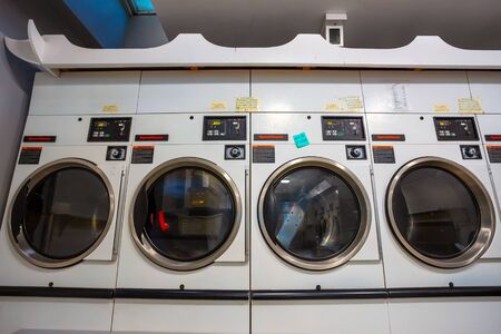 London, UK - May 19 2018: Row of coin laundries and cloth dryers in a self-service launderetteのeditorial素材