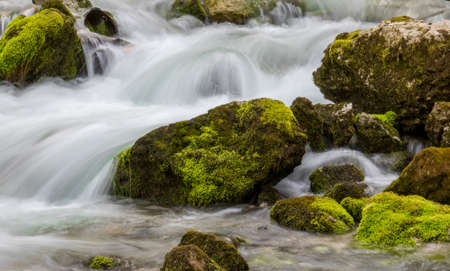 water flowing over rocks filled with mossの写真素材
