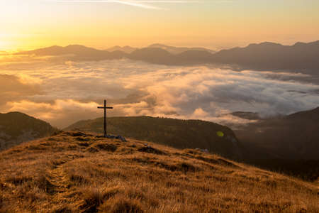 Sunlit grass with cross on top of a mountain Ogradi, Sloveniaの写真素材