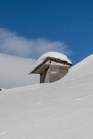 Small mountain cabin covered in snow, Bohinj mountainsの写真素材