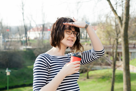 A girl in a striped T-shirt is drinking coffee with a blurred backgroundの写真素材