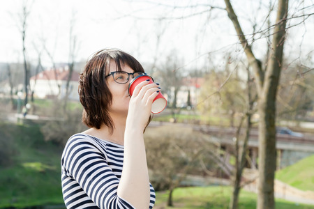 A girl in a striped T-shirt is drinking coffee with a blurred backgroundの写真素材