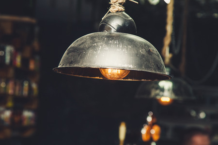 Lamp of Edison with a glowing thread under a lampshade. In the blurred background of a cafeの写真素材