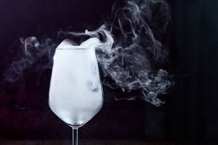In a wine glass, developing smoke. On a black backgroundの写真素材
